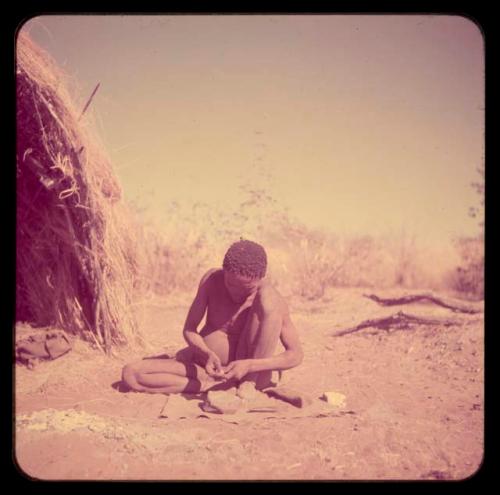 Arrows: Man working, with a stone anvil on the ground in front of him