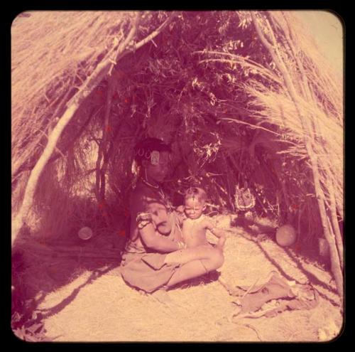 Children, Mother and children: Woman sitting inside a skerm, holding a child