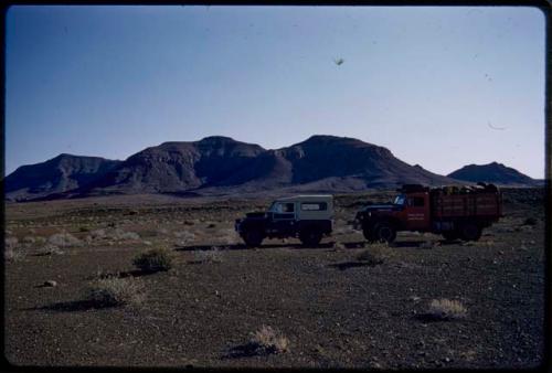 Expedition trucks, with hills on the west side of the Baynes Mountains in the distance