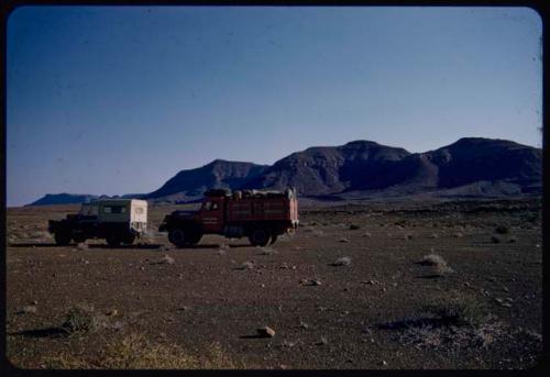 Expedition trucks, with hills on the west side of the Baynes Mountains in the distance