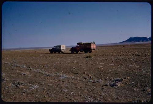 Expedition trucks, with hills on the west side of the Baynes Mountains in the distance