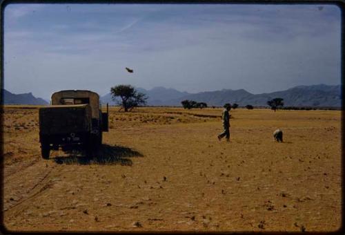 Charles and Rene Koch looking for beetles in the grass near an expedition truck