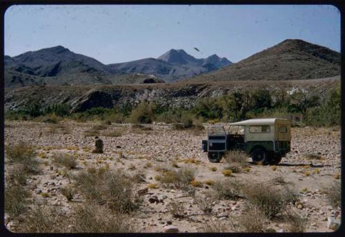 Charles Koch kneeling near the expedition Land Rover