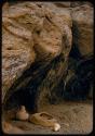 Baskets and a gourd on the ground at the mouth of a cave