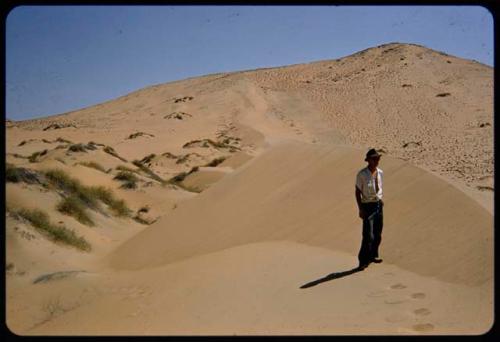 Kurt Ahrens standing on a sand dune, with the dune ridge behind him