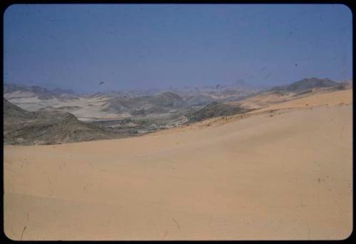 Sand dune, with hills across the Kunene River in the distance