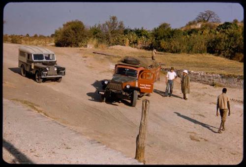 Expedition trucks (Land Rover and Dodge) waiting to cross the Kunene River on a pont