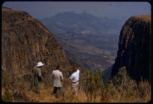 Charles Koch and two other people standing and looking at the Bimbe Gorge, also called Alto Bimbe; cliff on the right is where three sub-chiefs jumped off at time of the great chief's death