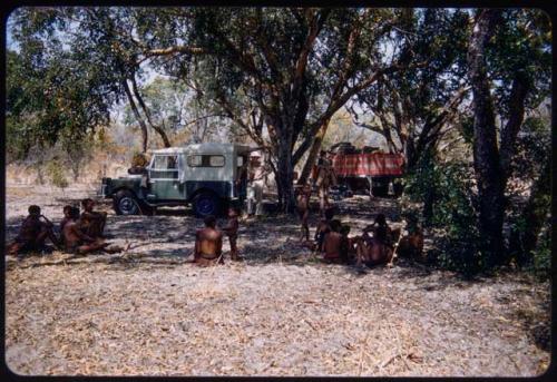 People sitting in Hambia's living place, with the expedition camp behind them