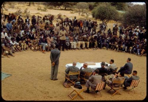 Omajetti indaba, group of men sitting and standing around Laurence Marshall, Colonel Hoogenhout (the South West African administrator), and John Neser sitting at a table