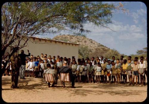 Children standing in line and singing for Colonel Hoogenhout (the South West Africa administrator) at a school