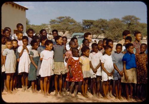 Children standing in line and singing for Colonel Hoogenhout (the South West Africa administrator) at a school, close-up