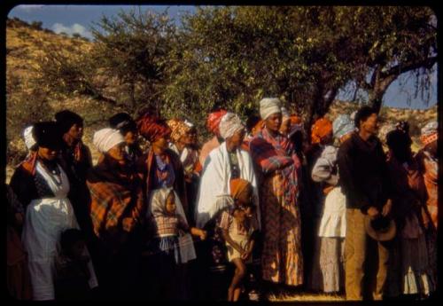 Franzfontein indaba, group of women and children standing, with a man standing in front of them