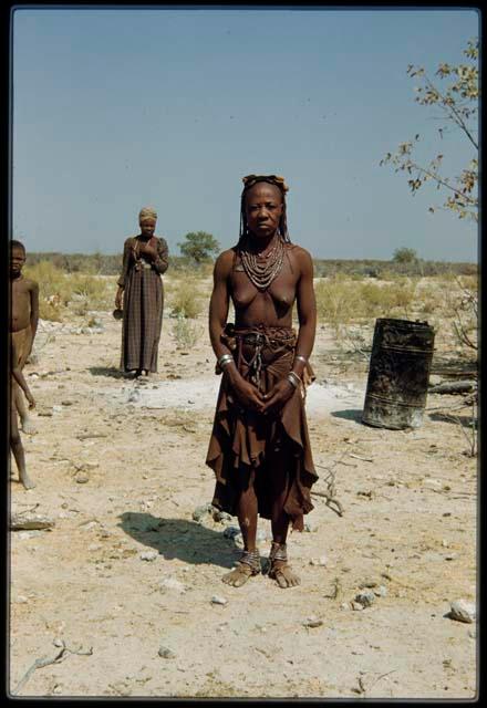 Himba woman standing, with a Herero woman standing behind her