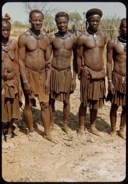 Three men standing in line to have their photographs taken, including the headman (left)