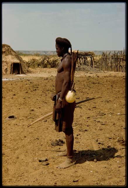 Young man standing, carrying a gourd tied to his belt