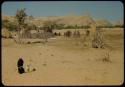 People standing and sitting in a village near the Gomatum River, distant view