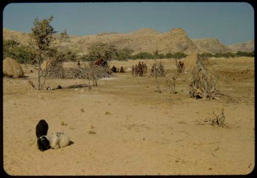 People standing and sitting in a village near the Gomatum River, distant view