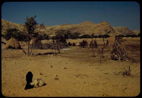 People standing and sitting in a village near the Gomatum River, distant view