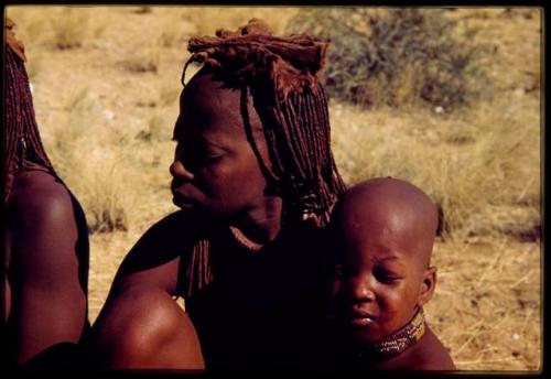 Woman wearing a headdress, with a baby tied to her back, close-up