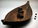 Carved wood boat model with figure seated in the middle