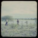 Expedition members, /Ti!kay, and Laurence Marshall standing at the edge of pan, seen from behind