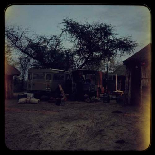 Trucks and huts, with a man standing in the middle