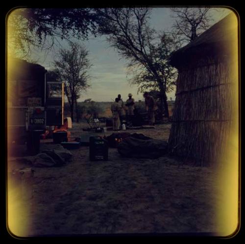 Trucks and huts, with a group of men gathered in the background