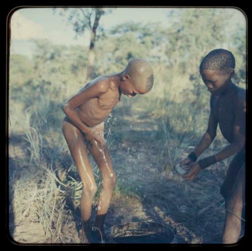 Boy bathing, helped by a friend