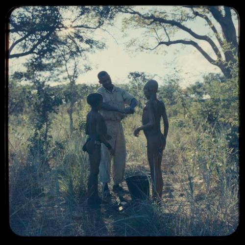 Kernel Ledimo standing with two boys who are in the middle of bathing