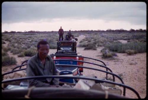 Dabe sitting on top of a truck, trucks behind him