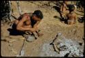 Spear, Making: "Gao Helmet" shaping an assegai blade, holding it on a stone with his foot, with two children in the background