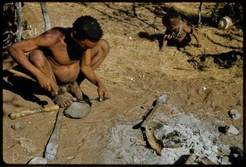 Spear, Making: "Gao Helmet" shaping an assegai blade, holding it on a stone with his foot, with his bed and a child in the background