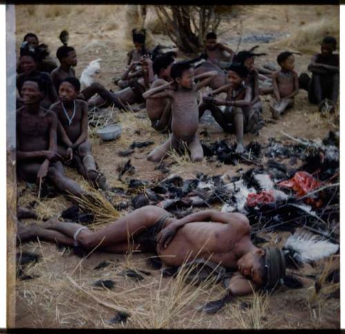 Hunting, Ostrich: "/Qui Hunter" sleeping after an ostrich hunt, with other people sitting behind him (half of stereoview 2001.29.5900)