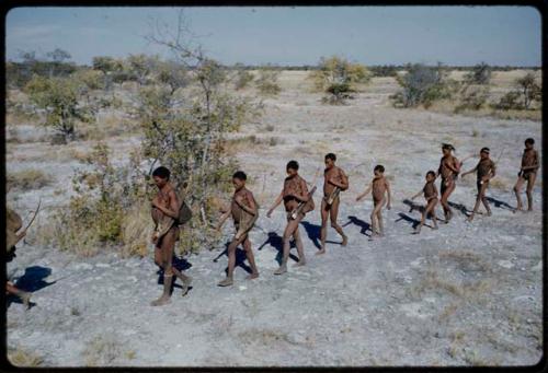 Walking: Men walking at the front of the line of the band moving, with the women following, including "Gao Medicine," /Gunda, an unidentified man, /Qui and Tsamgao (≠Toma's son)