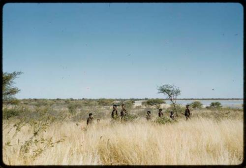 Walking: Group of women and children returning from a waterhole, with a pan filled with water in the background