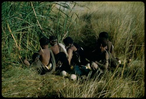 Water: Three men filling ostrich egg shells at a waterhole, with two women sitting behind them