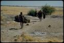 Water: People walking away from a waterhole, with Gautscha Pan in the distance