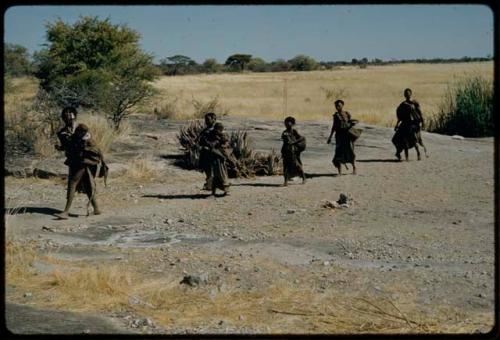 Water: //Kushay carrying a bowl, walking with other women away from a waterhole