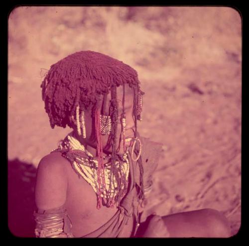 Children, Portraits: Girl wearing bead ornaments hanging down across her face and white necklaces around her neck, with red powder in her hair