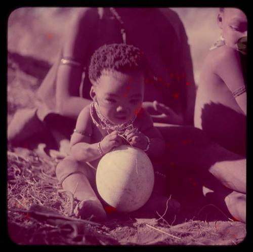 Children, Portraits: Bau's baby sitting and holding an ostrich eggshell