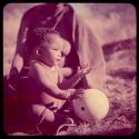 Children, Portraits: Bau's baby sitting and holding an ostrich eggshell, profile