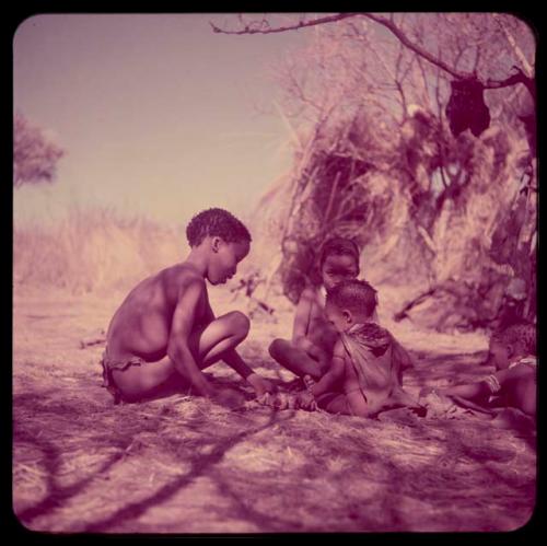 Children, Toys, Playthings: Tsamgao and /Gaishay playing with a toy car, sitting with !Ungka Norna and another baby