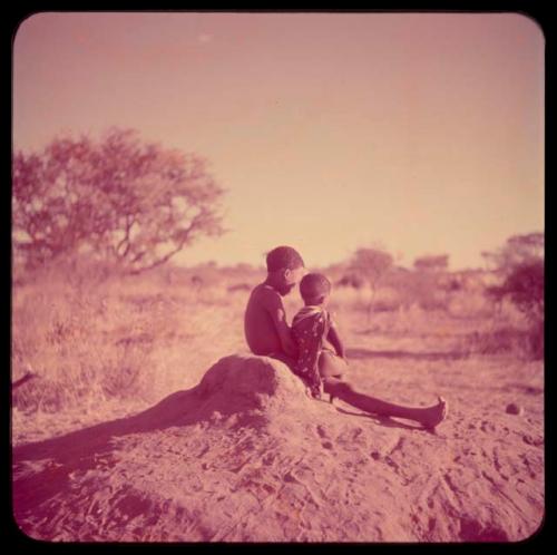 Children, Fathers and Sons (Boys): Boy holding a baby on his lap, sitting on a termite mound