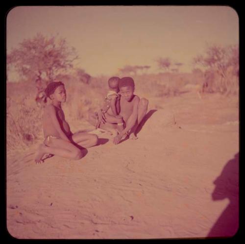 Children, Fathers and Sons (Boys): Boy holding a baby on his lap, sitting on a termite mound with /Qui (son of "/Gao Music")