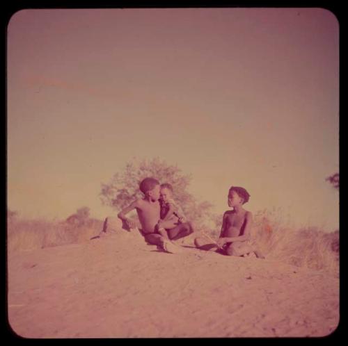 Children, Fathers and Sons (Boys): Boy holding a baby on his lap, sitting on a terminte mound with /Qui (son of "/Gao Music")