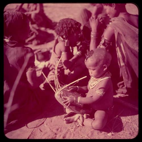 Children, Music: /Gaishay (Di!ai's son) playing the //guashi, with N!ai and another girl sitting behind him delousing a third girl