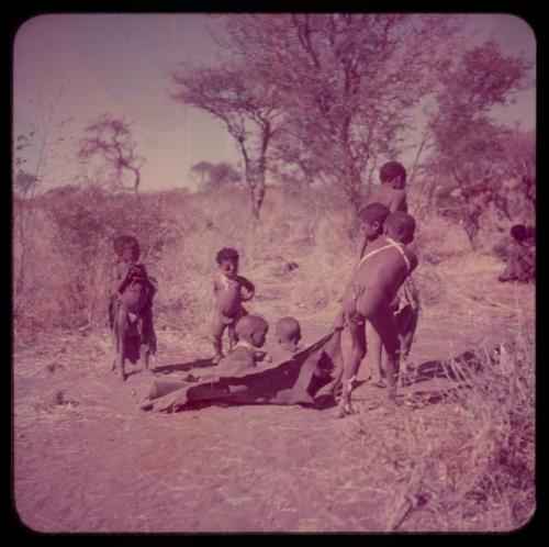 Children, Toys, Playthings: Three boys pulling two little boys on a kaross, with Be and Bau standing and watching