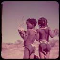 Children, Music: Two girls standing, one playing the //guashi, view from behind