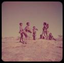 Children, Music: Boys and girls dancing on a ledge by a waterhole, one boy playing a //guashi